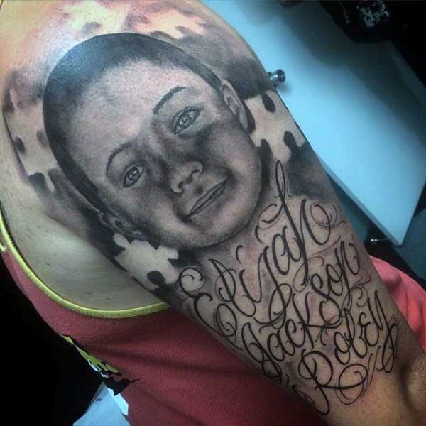 Gray washed style cute looking boy portrait tattoo on shoulder stylized with lettering and puzzle pieces