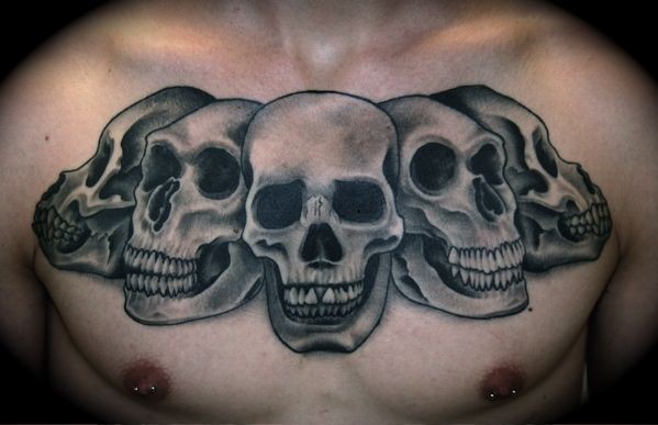 Gray washed style detailed chest tattoo of various skulls