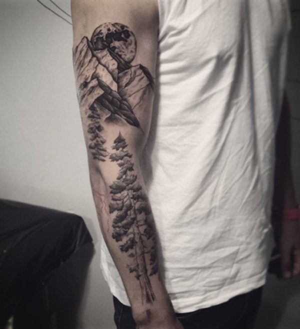 Gray washed style forearm tattoo of trees with mountains