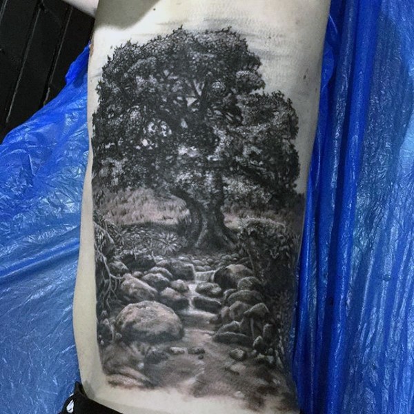 Gray washed style side tattoo of countryside tree and little stream