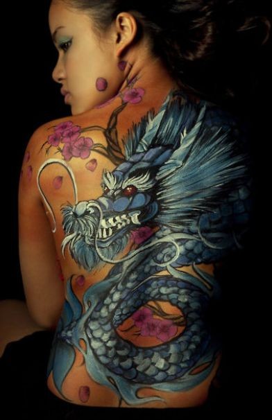 Tatuaggio impressionante sulla schiena della ragazza il dragone blu e la sakura fiorita