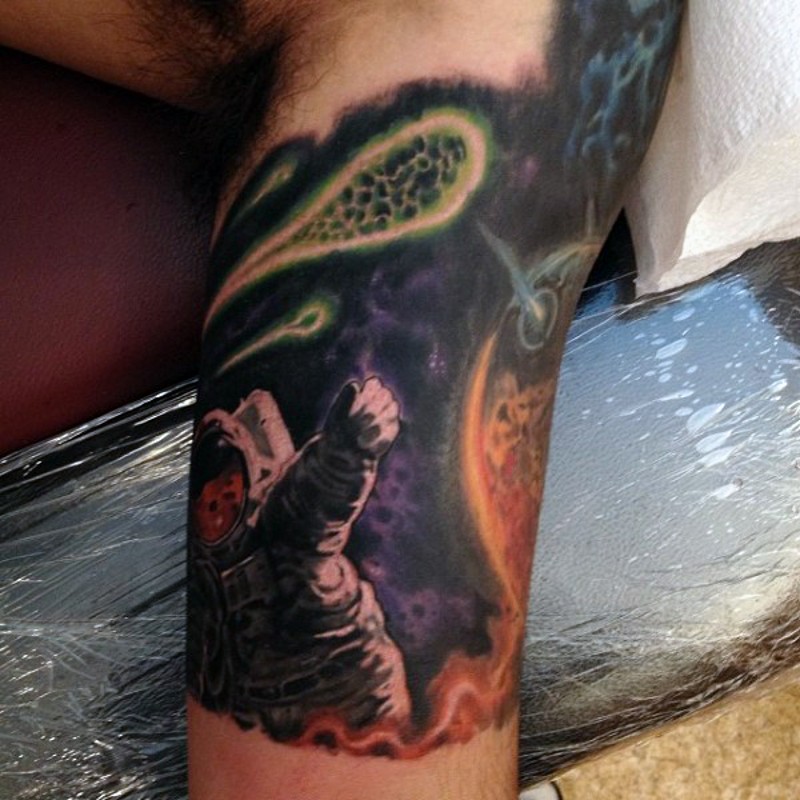 Tatuaje en el brazo,
astronauta en el espacio y cometas, diseño multicolor