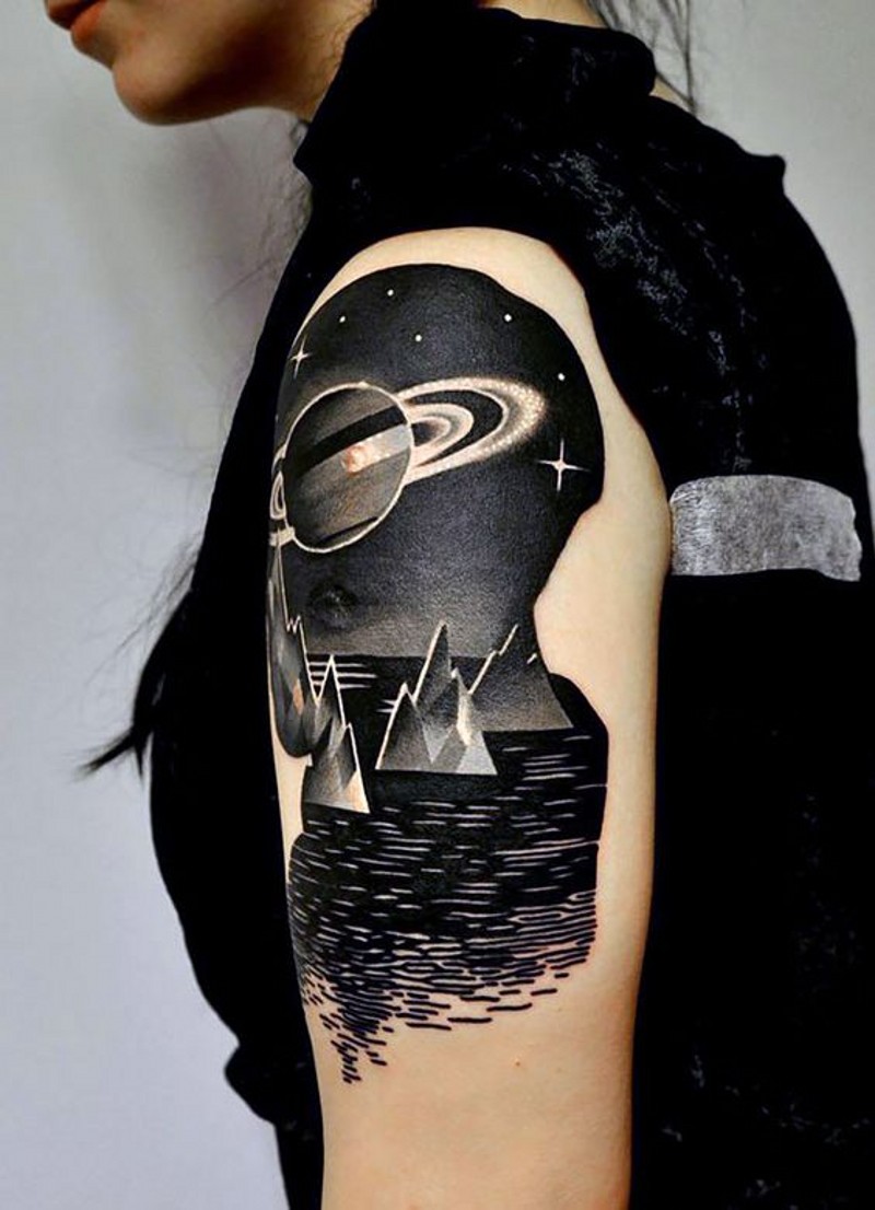 Tatuaje en el brazo,
océano oscuro con planeta grande y estrellas