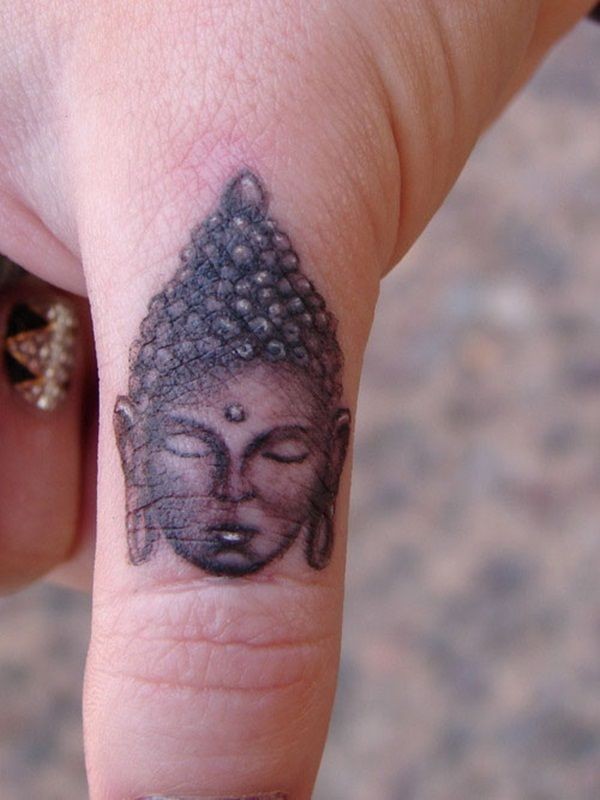 Tatuaje en el dedo, cara de buda, tinta gris