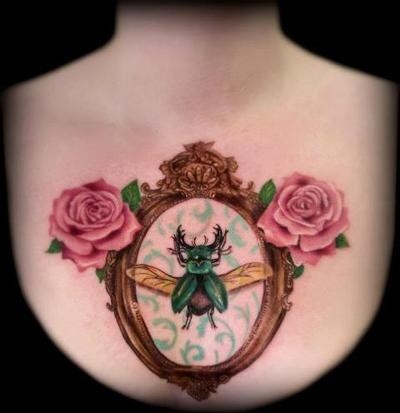 Green beetle on a mirror with roses tattoo on chest
