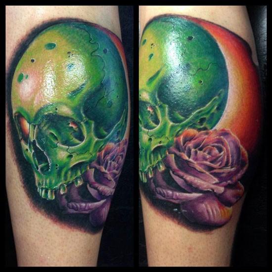 Green colored leg tattoo of big human skull and violet rose