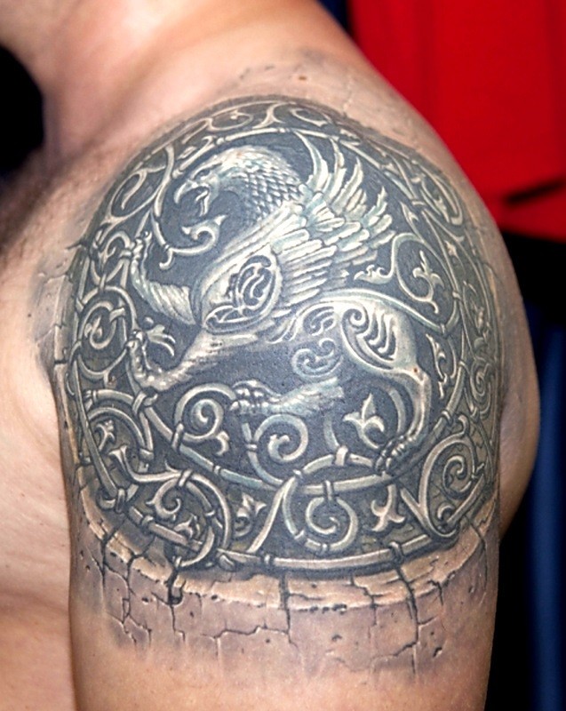 Griffin tattoo on stone with curls on shouder