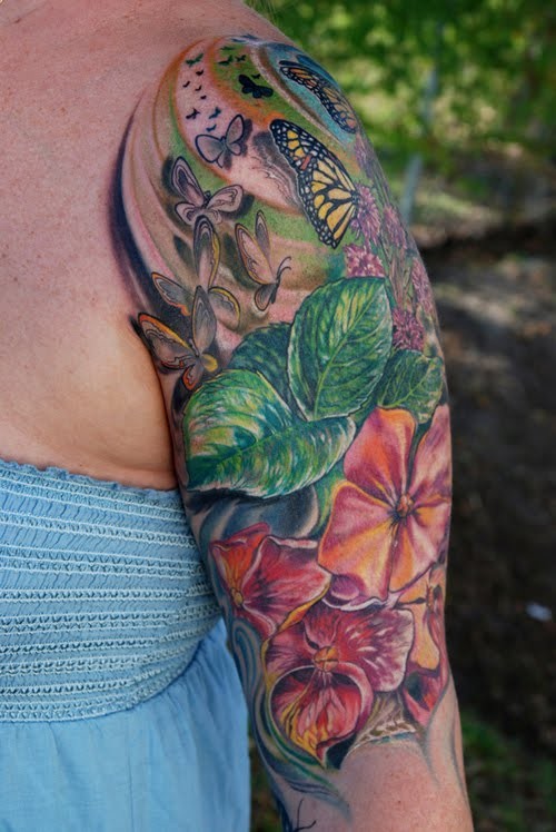 Tatuaje en el brazo, flores tropicales con hojas y mariposas