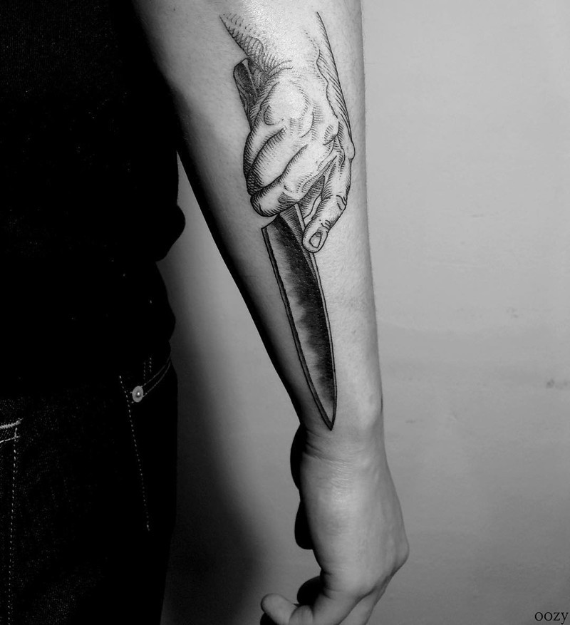 Hand mit scharfem Messer detailliertes Tattoo am Unterarm Zone