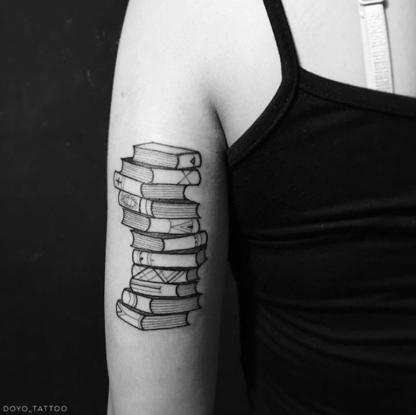 Hoher Stapel aus schwarzen und weißen Büchern Tattoo am Bizeps mit kleinen Details