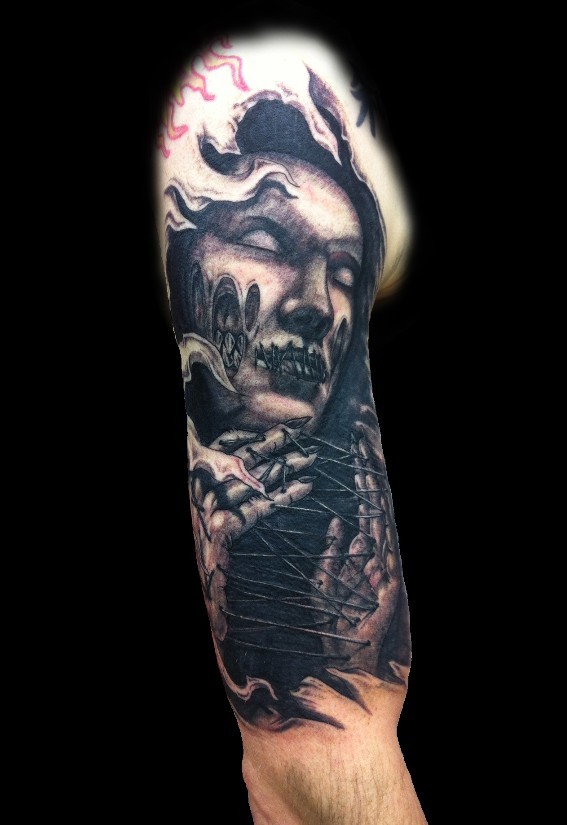 Horror movie like black ink horrifying witch tattoo on upper arm