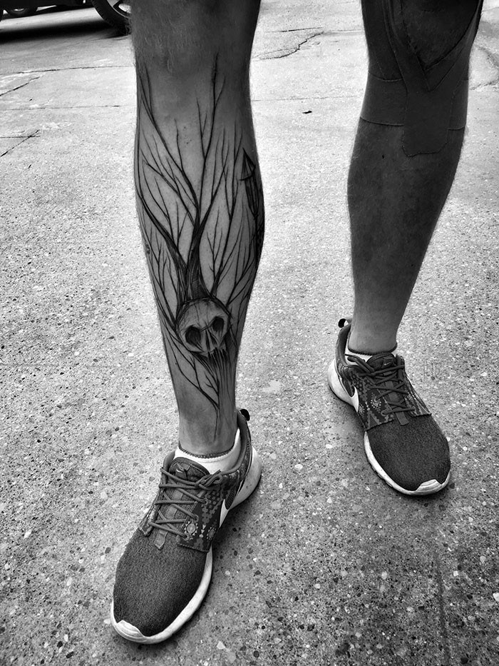 Tatuaje de la pierna de tinta negra estilo terror del cráneo humano con árbol de Inez Janiak