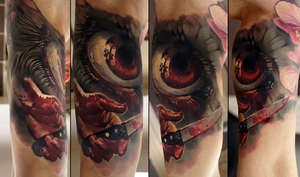 Horror style creepy looking biceps tattoo of bloody eye with knife