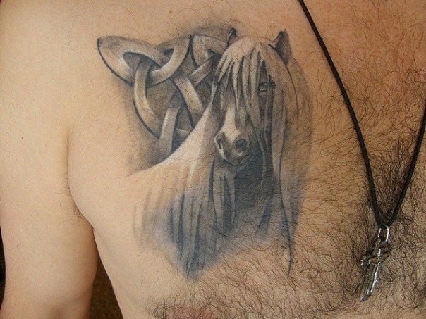 Tatuaje en el pecho,  caballo blango con crin larga y un símbolo metálico