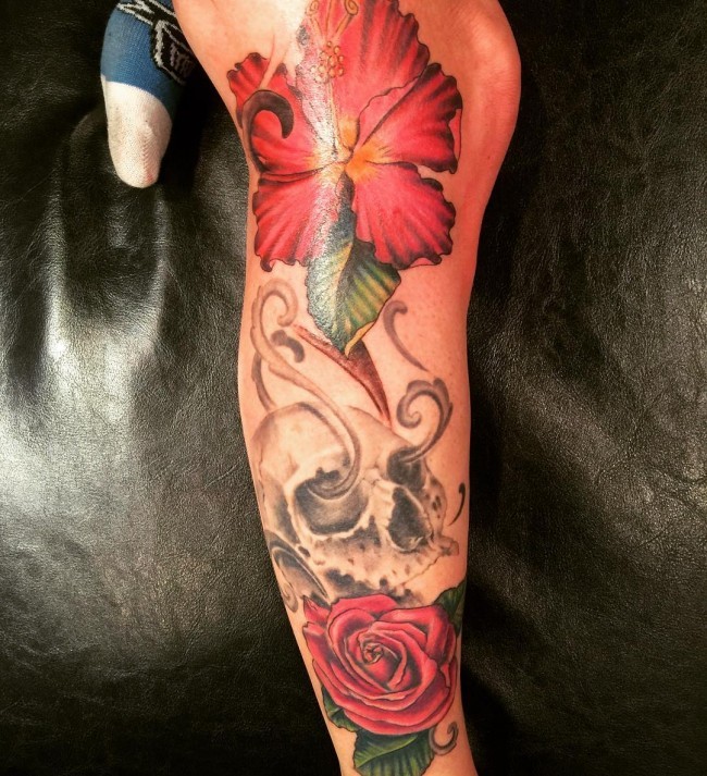 Human skull with pink hibiscus and rose flower leg length tattoo in 3D realistic technique