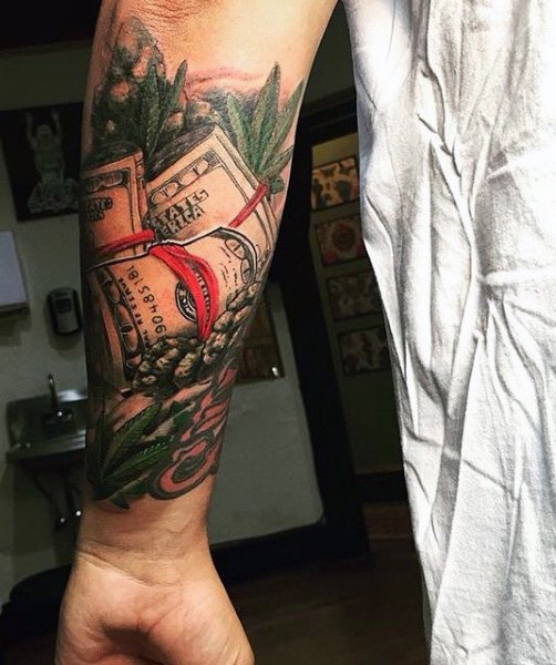 Hundred dollars banknotes and weed leaves colored lifelike tattoo on arm