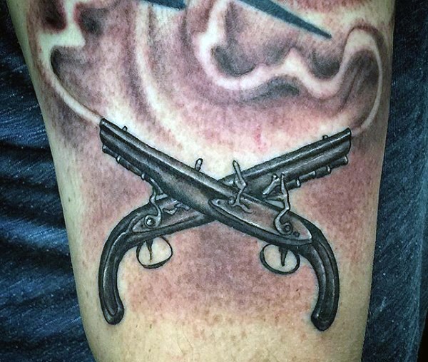 Illustrative style black ink arm tattoo of crossed antic pistols