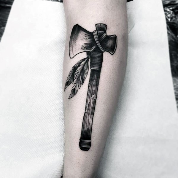 Illustrative style black ink Indian axe tattoo on leg