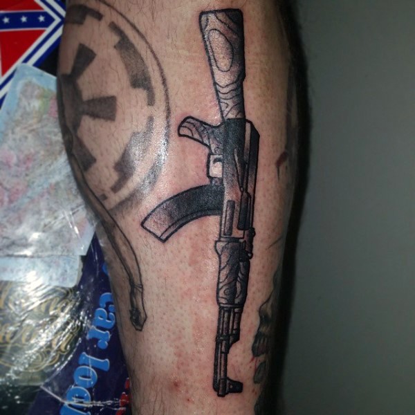 Illustrative style black ink leg tattoo of AK rifle