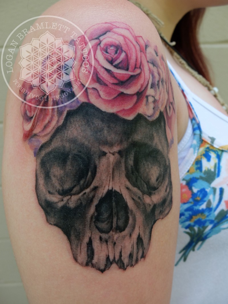 Illustrative style black ink shoulder tattoo of skull with roses