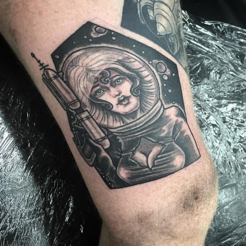 Illustrative style black ink thigh tattoo of space woman with blaster
