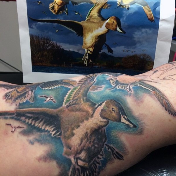 Illustrative style colored biceps tattoo of flying ducks