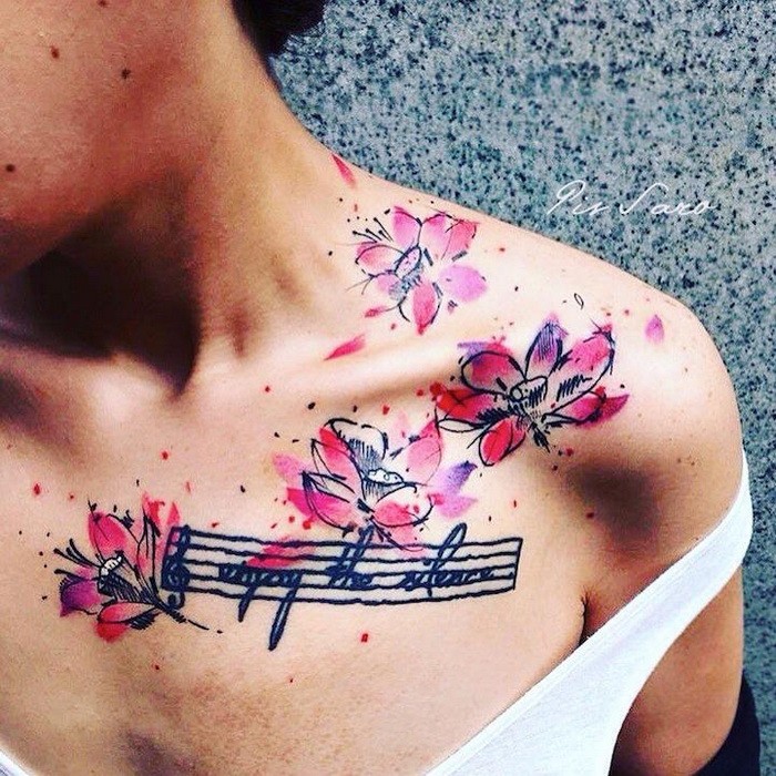 Illustrative style colored collarbone tattoo of pink flowers with music note and lettering