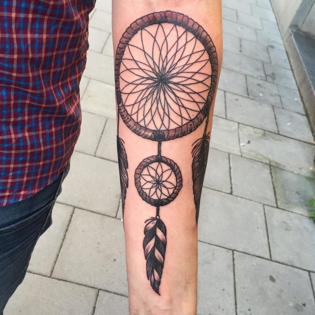 Illustrative style colored dream catcher tattoo on forearm
