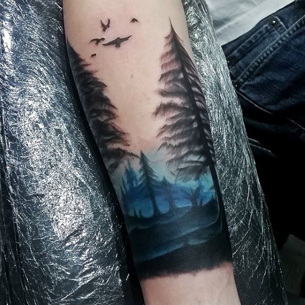 Illustrative style colored forearm tattoo of natural forest with birds