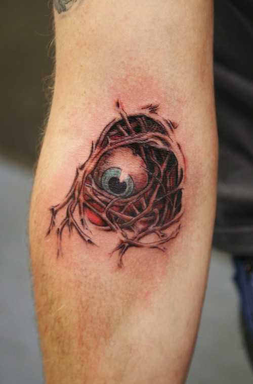 illustrative style colored forearm tattoo of creepy demonic eye