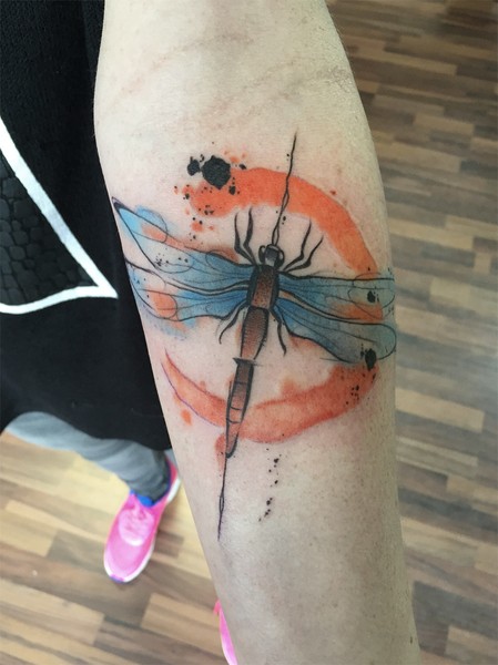 Illustrative style colored forearm tattoo of dragonfly