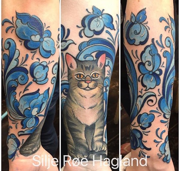 Illustrative style colored forearm tattoo of cat with flowers and plants