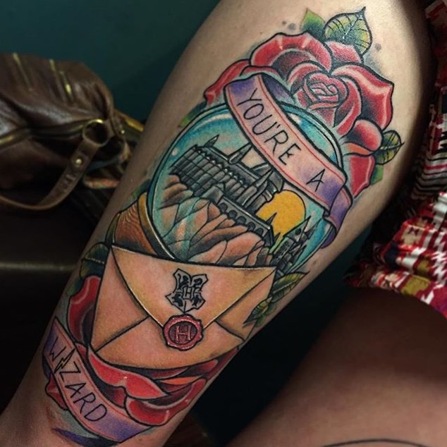 Illustrative style colored Harry Potter movie Hogwarts school tattoo on thigh with lettering