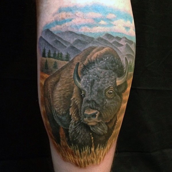 Illustrative style colored leg tattoo of wild bull with mountains