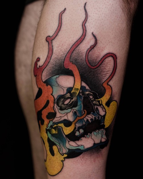 Illustrative style colored leg tattoo of human skull with flames