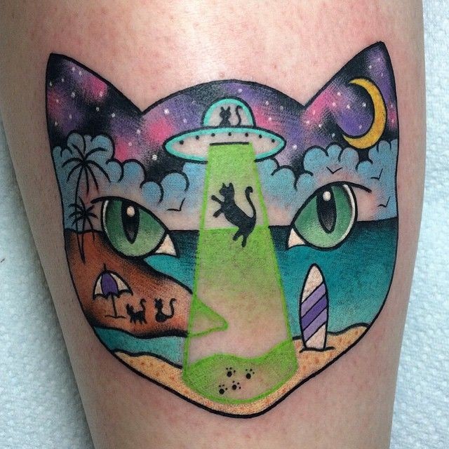 Illustrative style colored leg tattoo of cat head stylized with alien ship with island