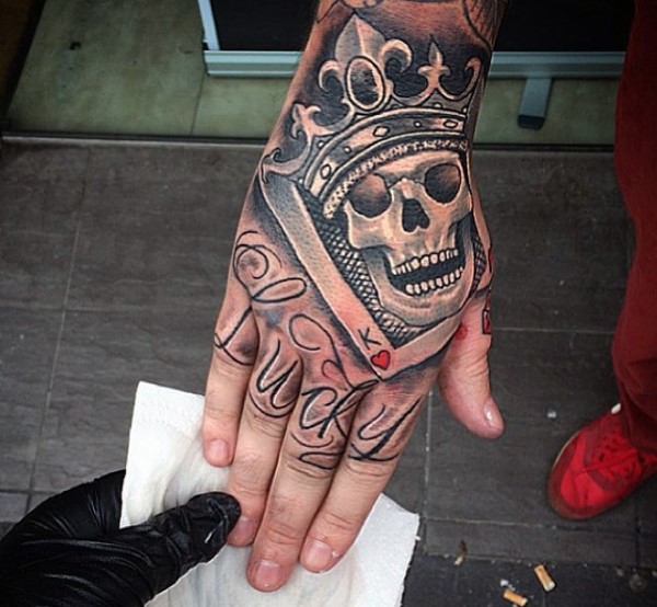 Illustrative style colored skull king with crown tattoo on hand with lettering