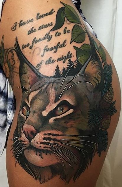 Illustrative style colored thigh tattoo of caracal with lettering and feather