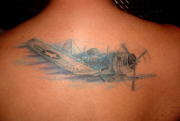 Illustrative style colored upper back tattoo of flying plane