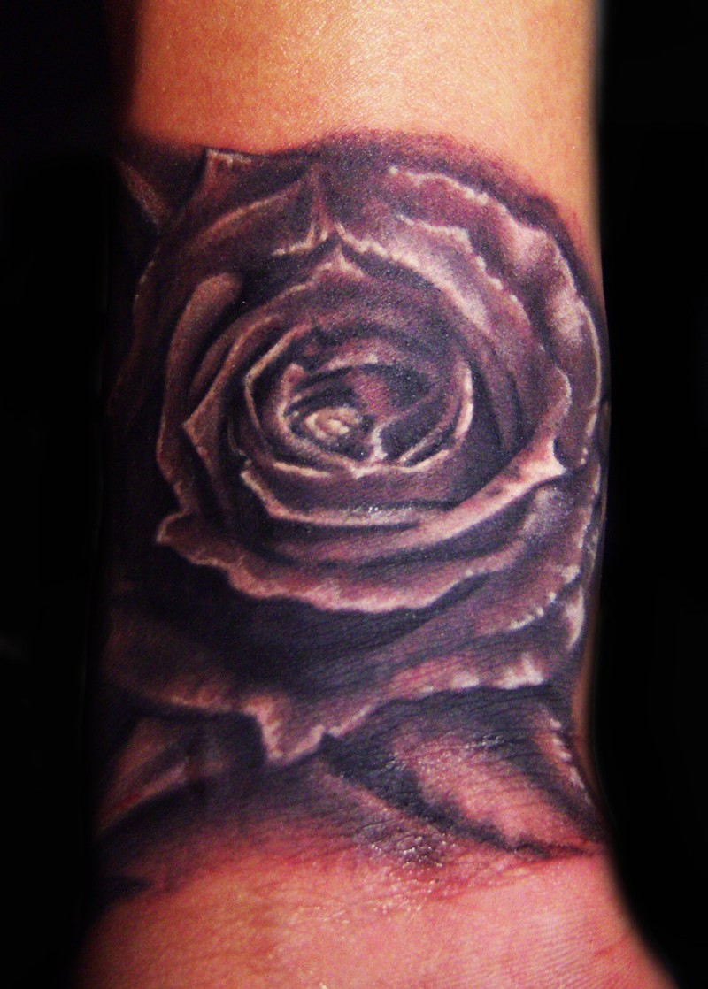 Illustrative style colored wrist tattoo of black rose