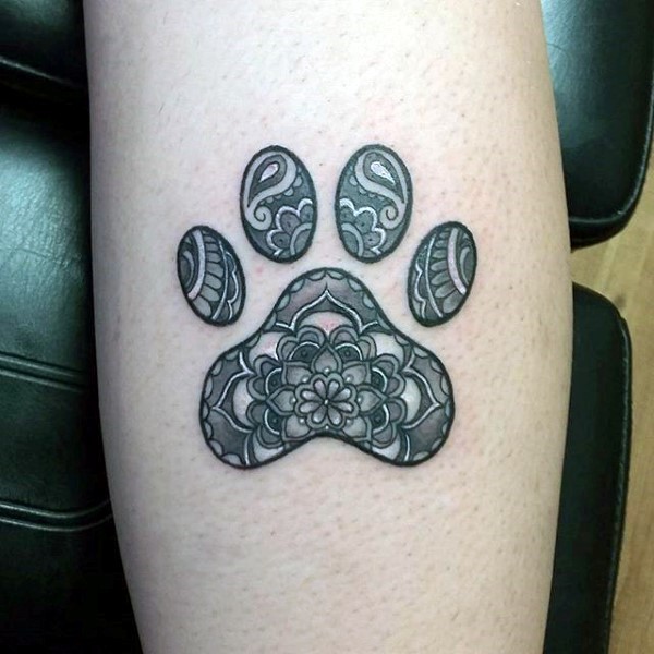 Illustrative style detailed leg tattoo of animal paw print stylized with ornaments