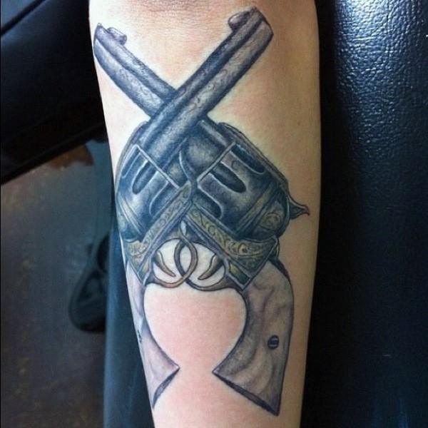 Illustrative style medium size colored forearm tattoo of crossed revolvers