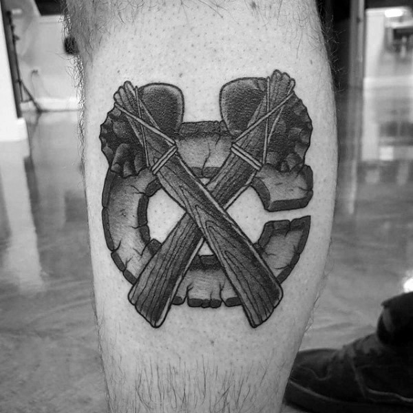 Impressive black ink leg tattoo of crossed stone axes with big letter