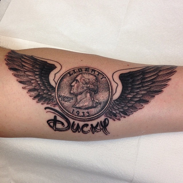 Impressive looking black ink forearm tattoo of antic coin with wings and lettering