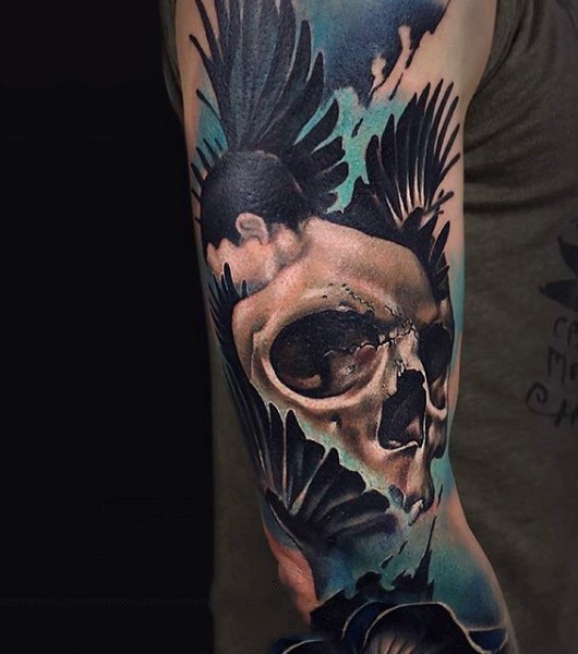 Tatuaje en el brazo, hosmbre con cráneo en la espalda y alas grandes