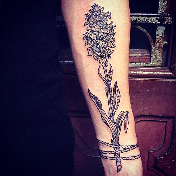 Impressive natural looking black and white forearm tattoo of roped flower