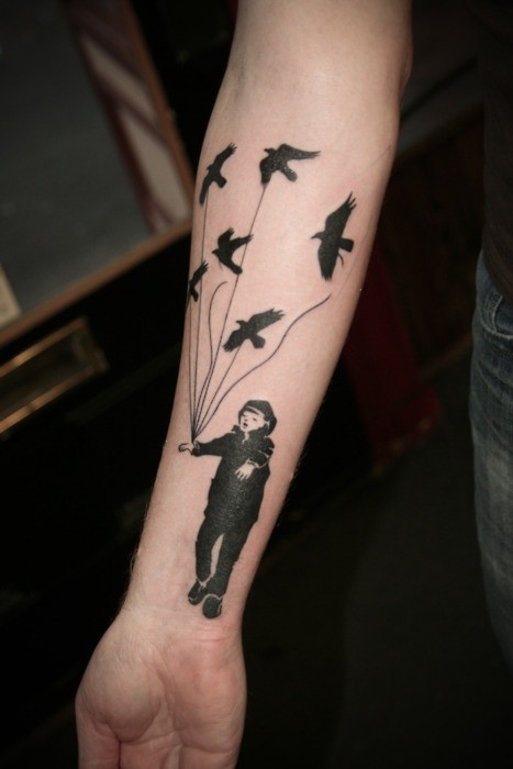 Impressive painted black ink boy with bird shaped balloons tattoo on arm