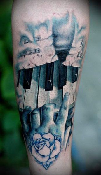 Impressive realism style colored piano key with playing hand tattoo on forearm
