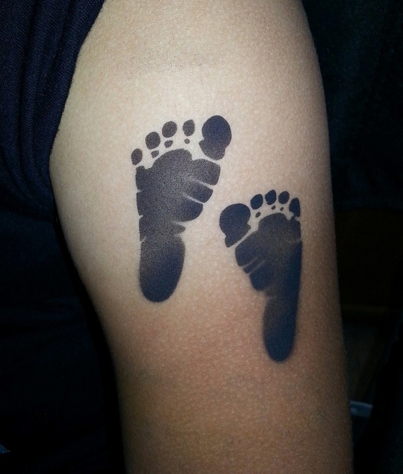 impronti di piedi bambino tatuaggio su spalla di uomo