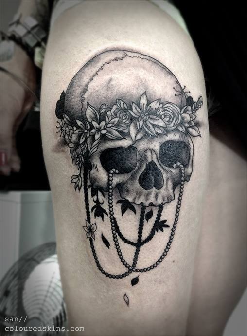 Unglaublicher detaillierter menschlicher schwarzer Schädel mit Blumen Tattoo am Oberschenkel mit Schmuck